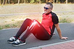 Jogger with sitting on road with knee injury